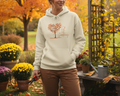Person wearing a hoodie with a tree design in an autumn garden setting