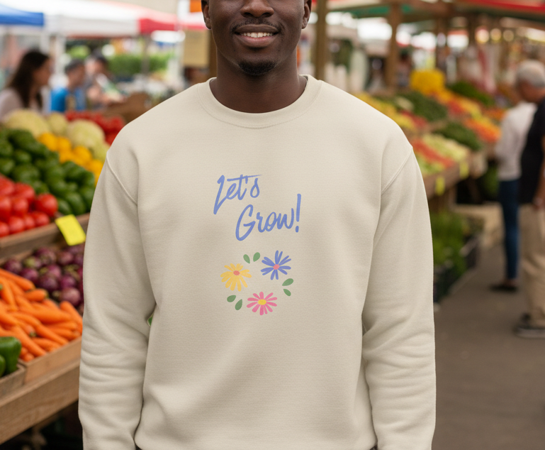 Person wearing a beige sweatshirt with 'Let's Grow!' text and floral designs in a market setting