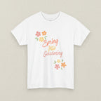 White t-shirt with 'Spring Into Gardening' text and floral designs on a white background