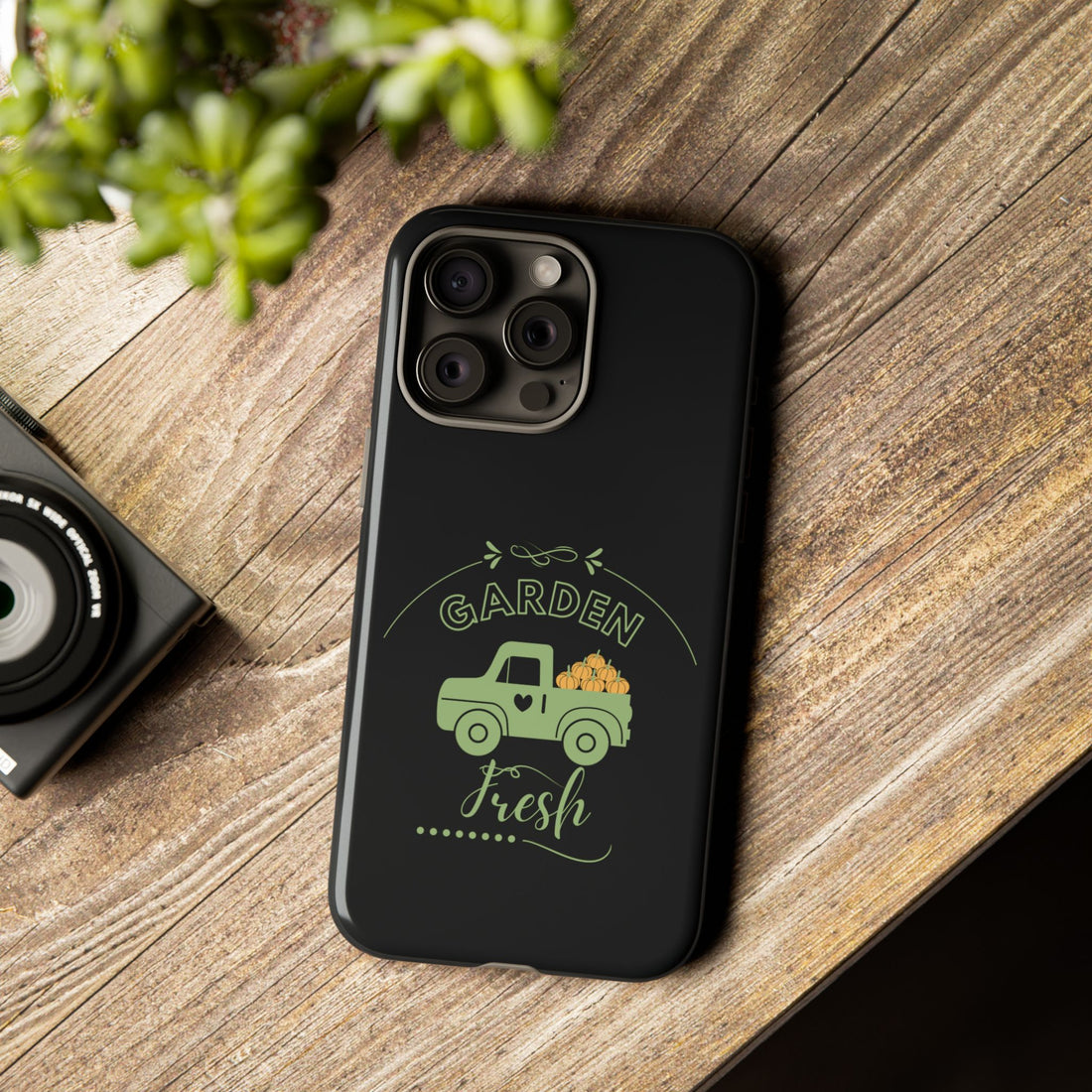 Black phone case with 'Garden Fresh' design on a wooden surface
