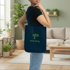 Woman holding a navy tote bag with 'Garden Strong' text in a living room setting