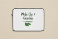 Laptop sleeve with 'Wake Up & Garden' text and leaf design on a white background
