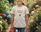 White t-shirt with 'Gardener in Training' text and tomato graphic on a beige background