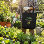 Person holding a tote bag with 'Daddy Gardener' text in a garden setting