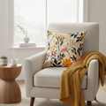 Beige armchair with a floral pillow and yellow blanket in a bright living room.
