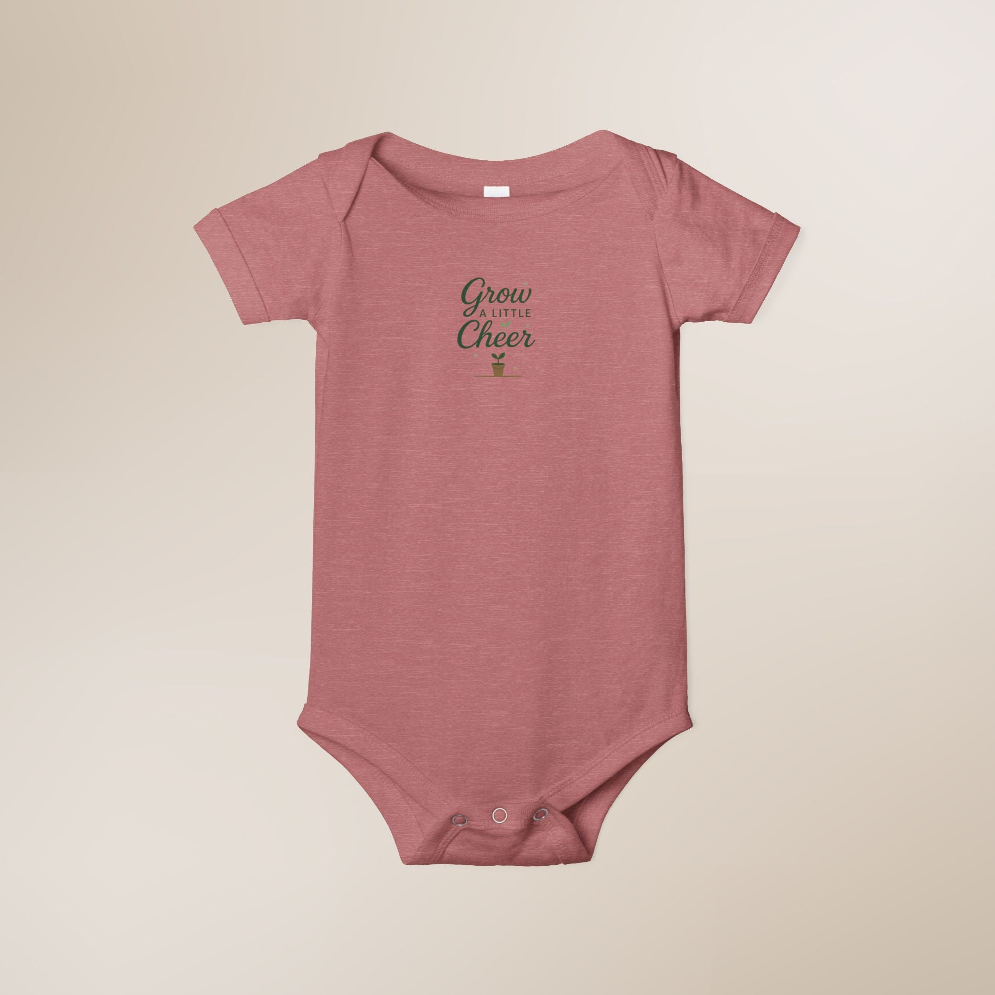Pink baby onesie with 'Grow a Little, Cheer' text on a beige background