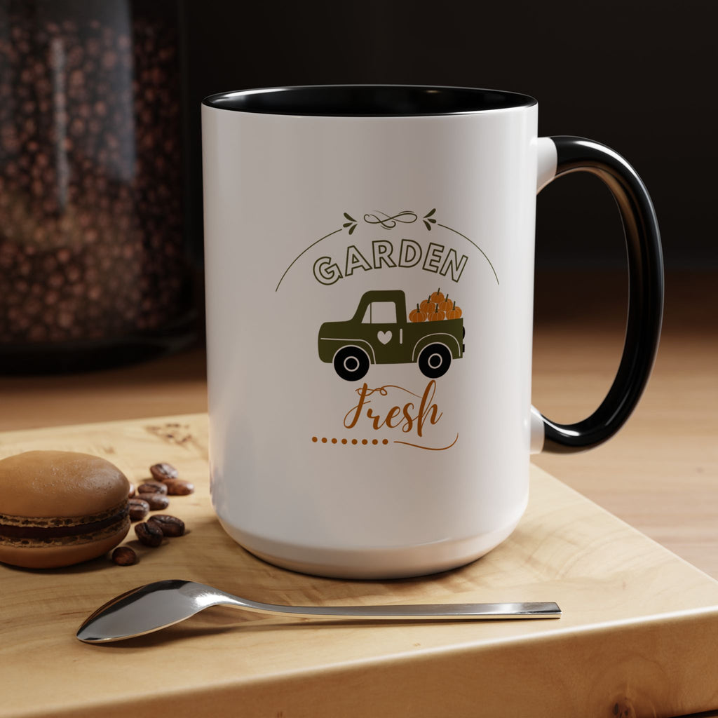 White mug with black interior and handle, featuring a truck and 'Garden Fresh' text, on a wooden surface with coffee beans and a spoon.