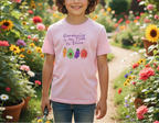 Child wearing a pink t-shirt with gardening-themed design in a garden setting