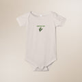 White baby onesie with green leaf design and text on a beige background