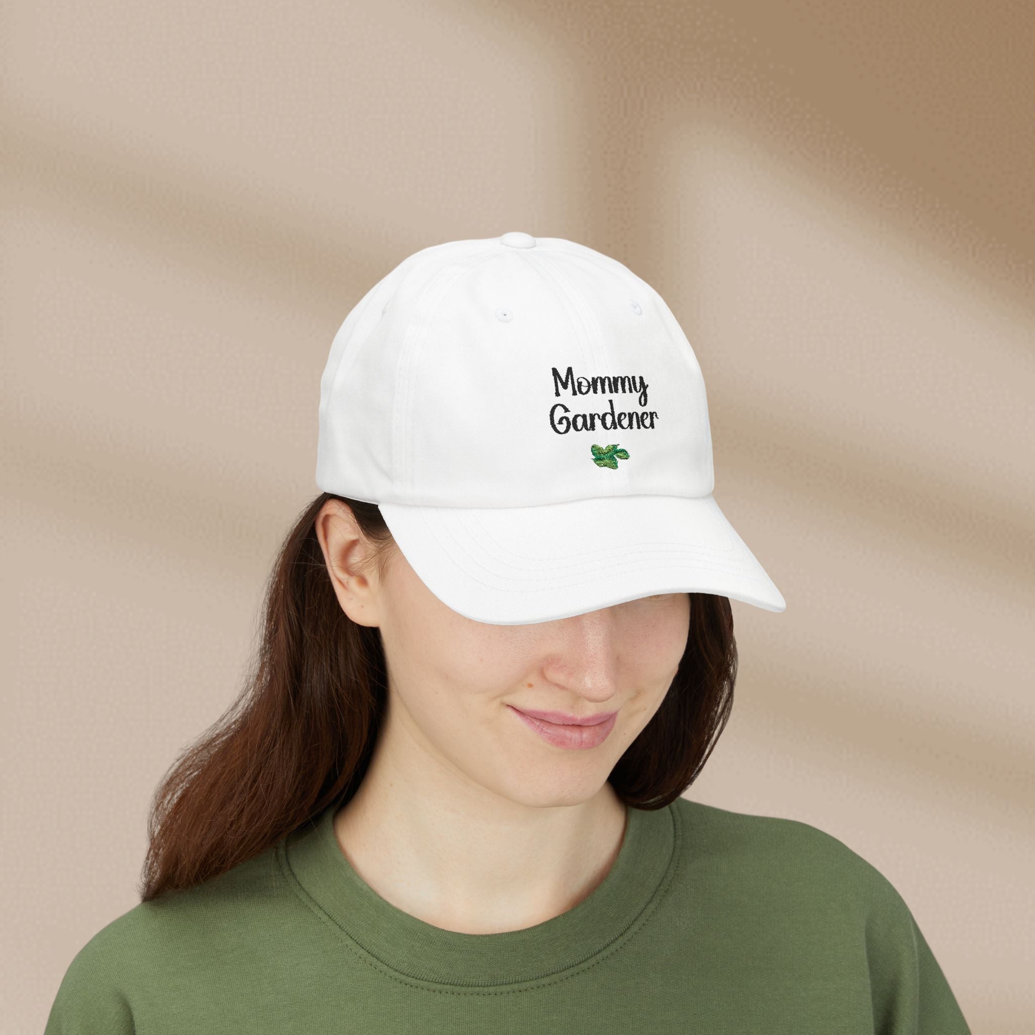 Person wearing a white cap with 'Mommy Gardener' text on a beige background