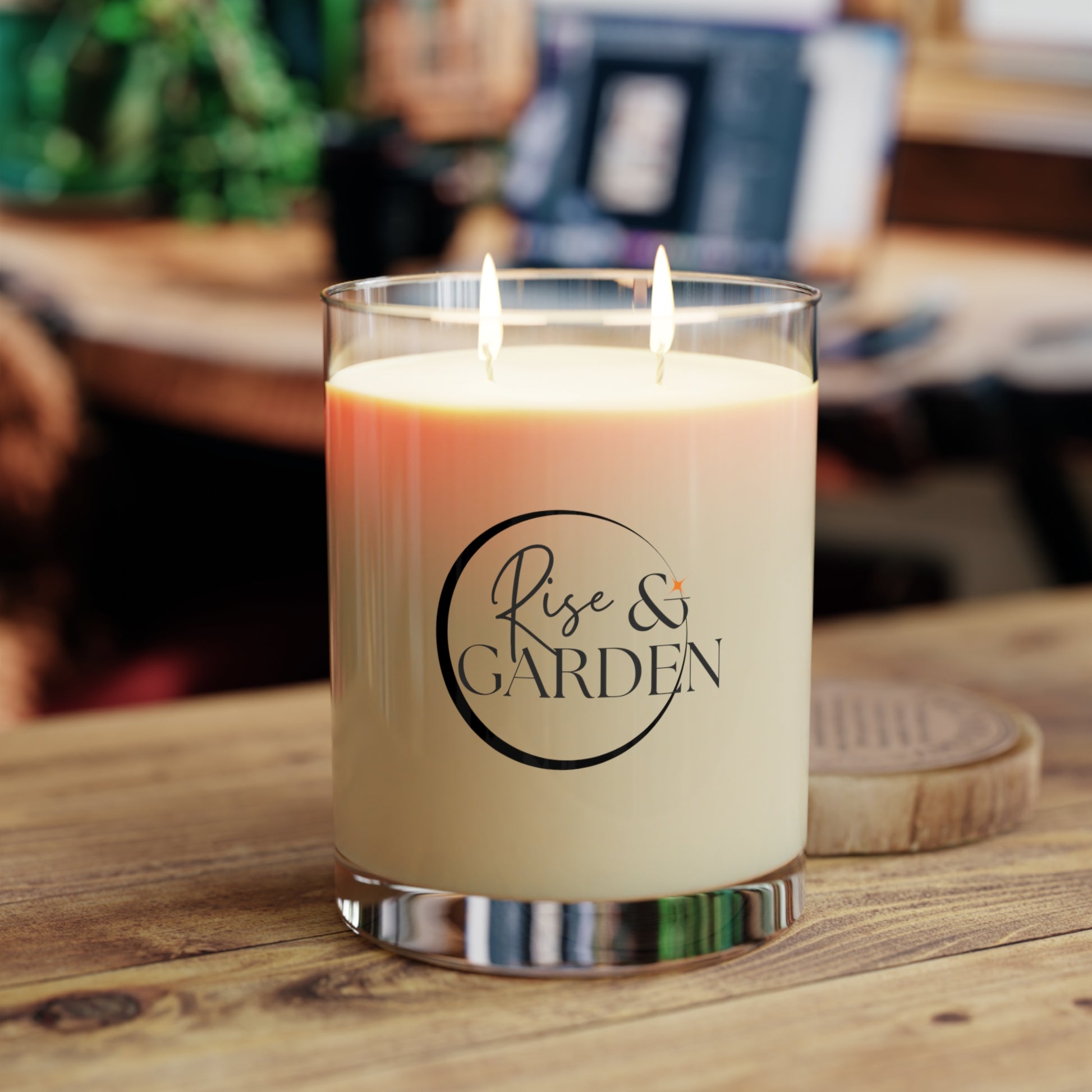 Candle with 'Rise & Garden' logo on a wooden surface