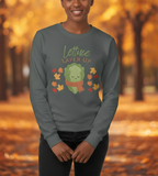 Person wearing a sweater with a lettuce graphic and 'Lettuce Layer Up' text in an autumn setting.