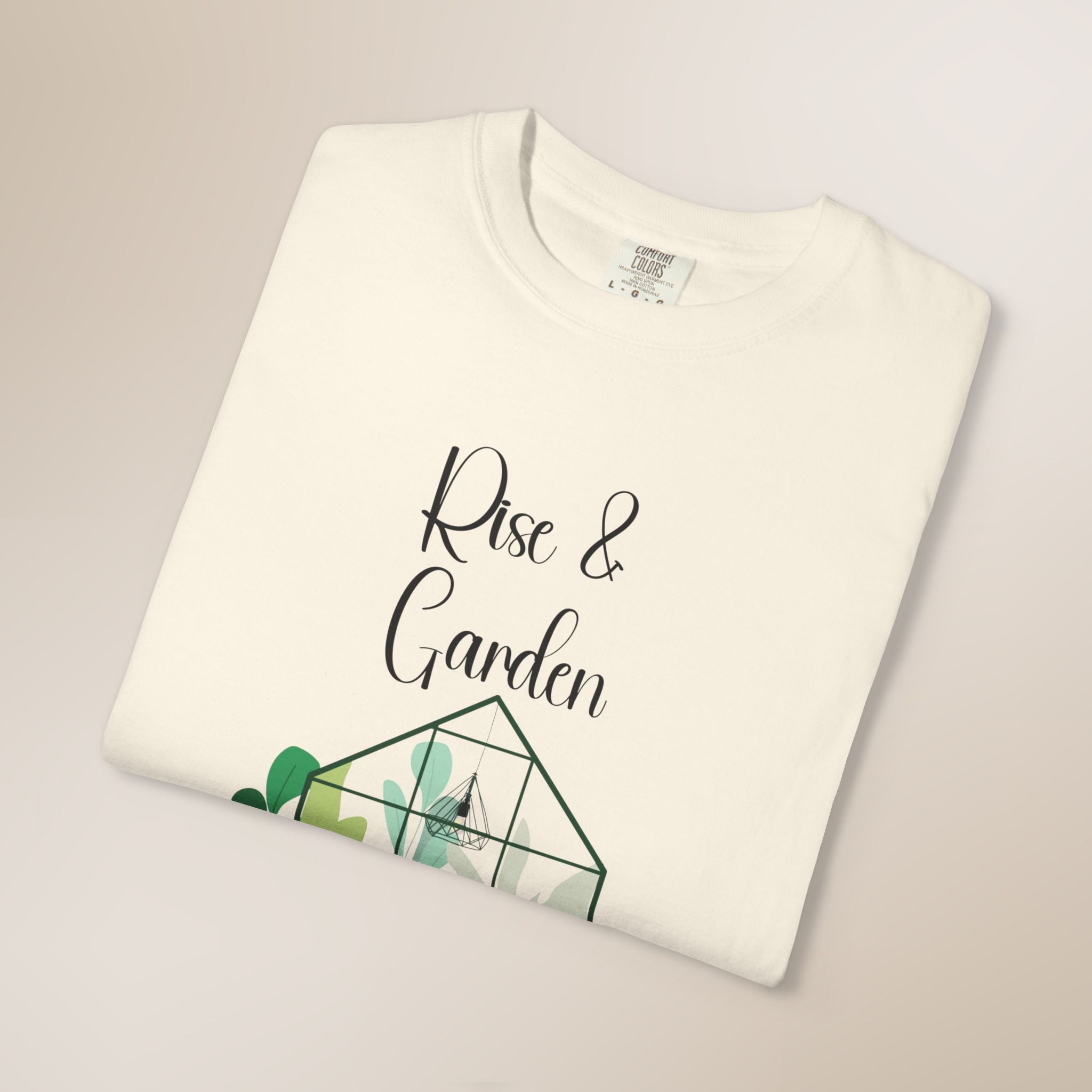White t-shirt with 'Rise & Garden' text and geometric plant design on a light gray background