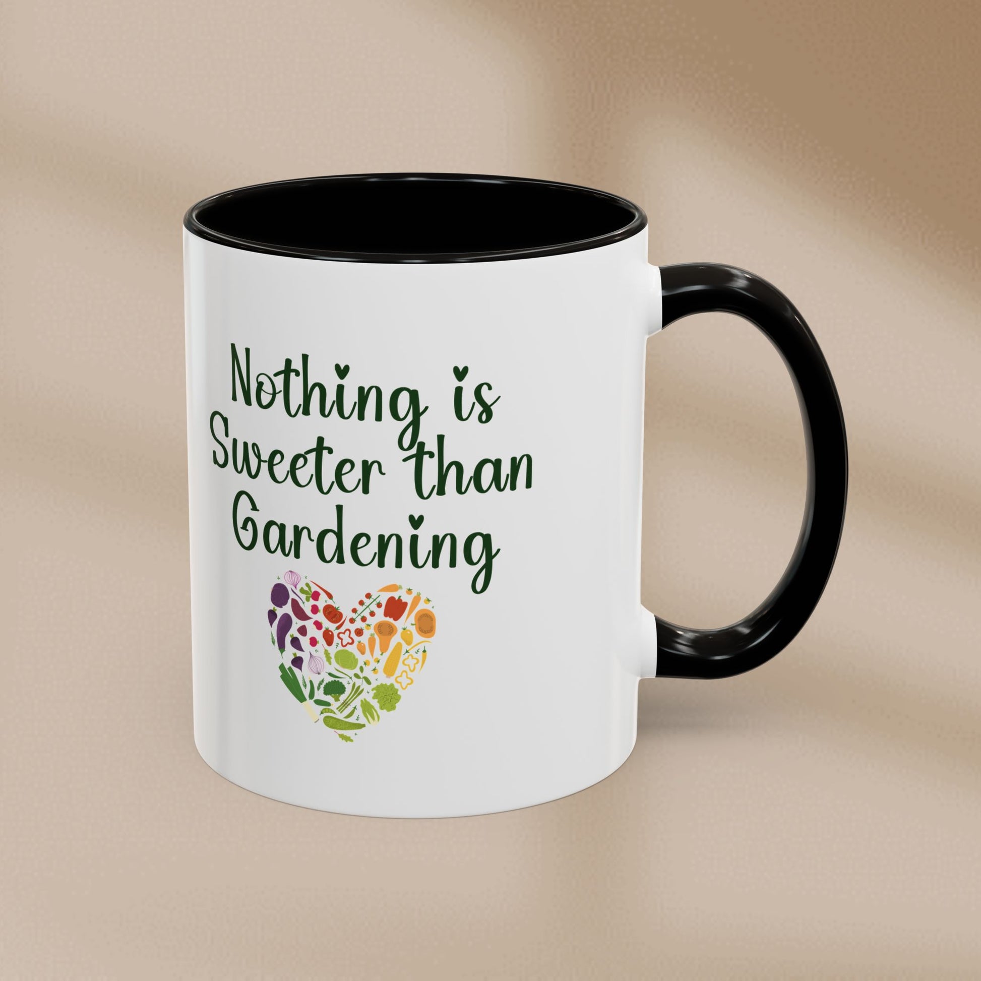White mug with black interior and handle, featuring 'Nothing is Sweeter than Gardening' text and a colorful heart design on a beige background.