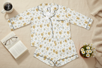 Floral pajama set on a wooden surface with a cup of coffee, book, and plant.