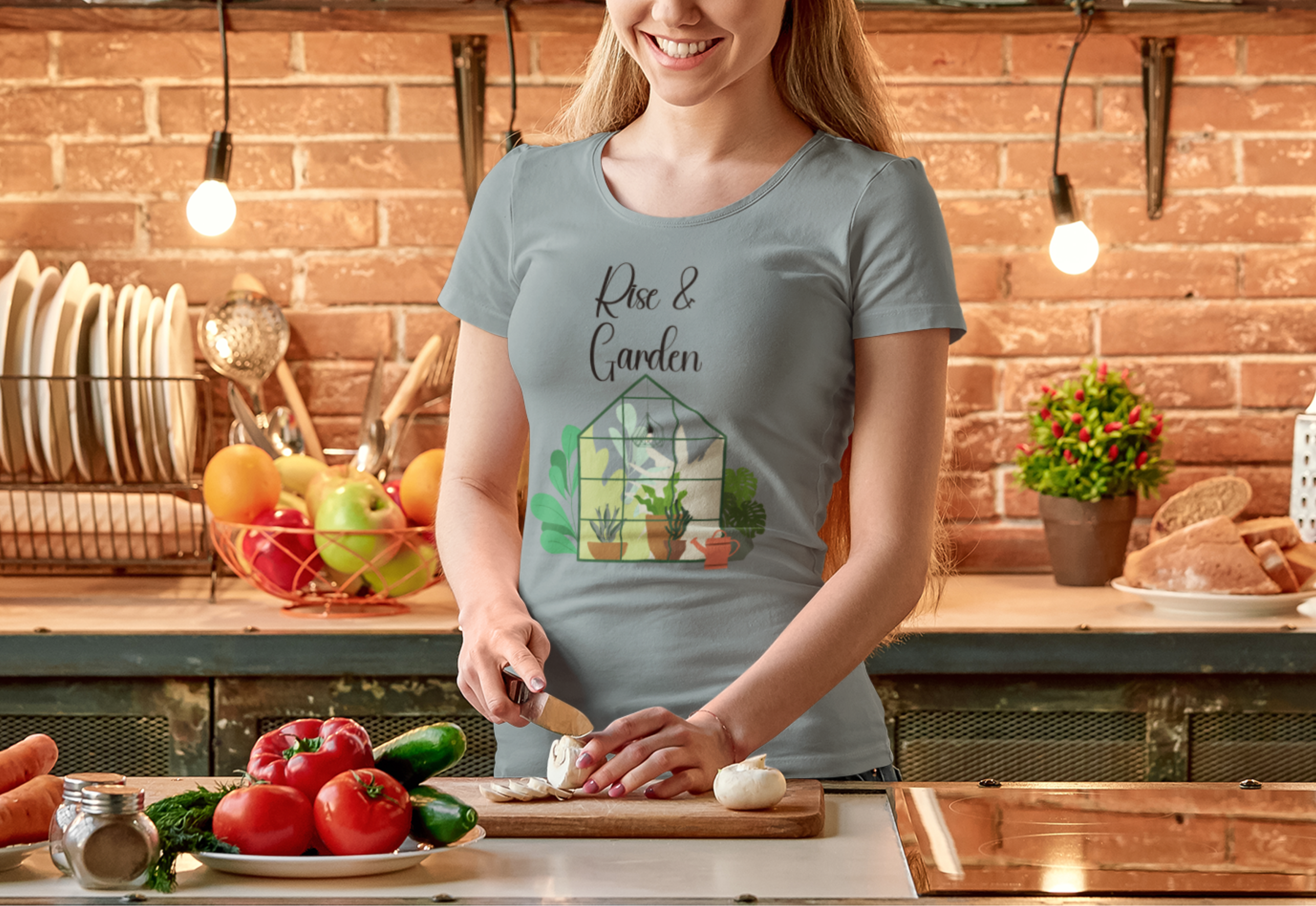 Woman in a kitchen wearing a t-shirt with a garden design, standing by a cutting board with vegetables.