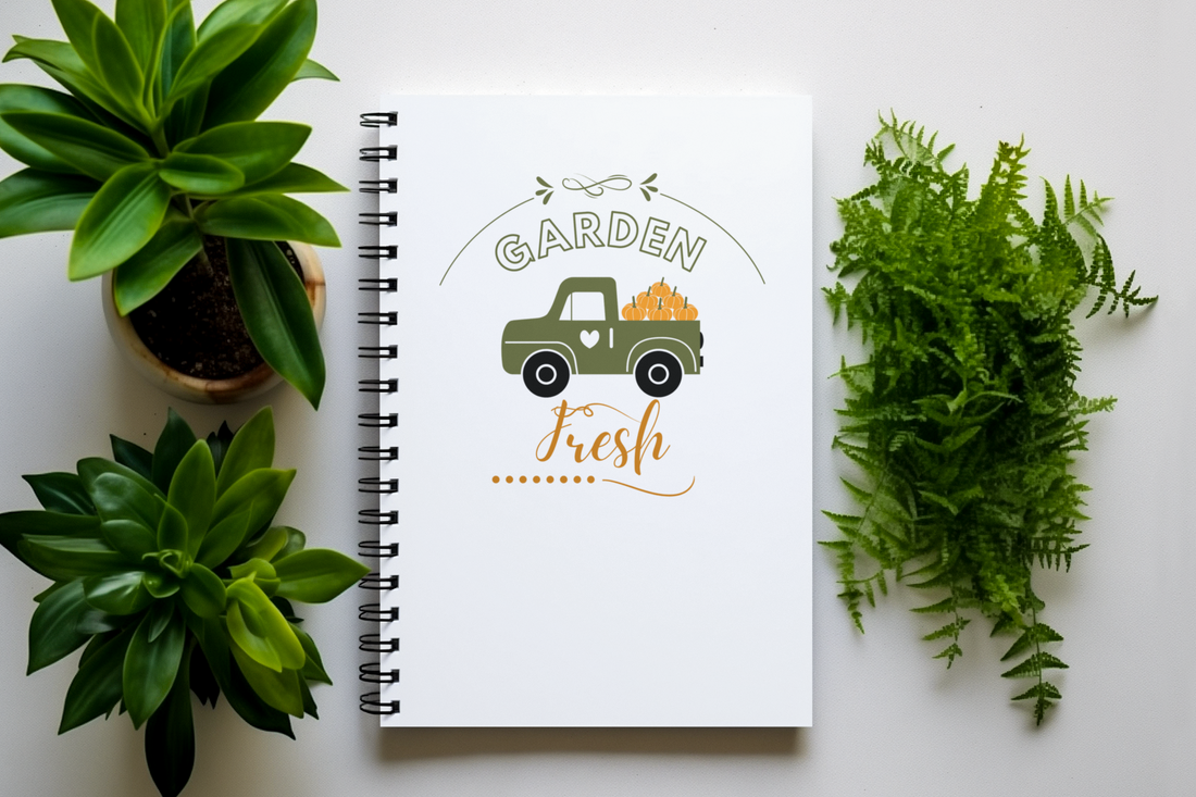 Notebook with 'Garden Fresh' design surrounded by green plants on a white background
