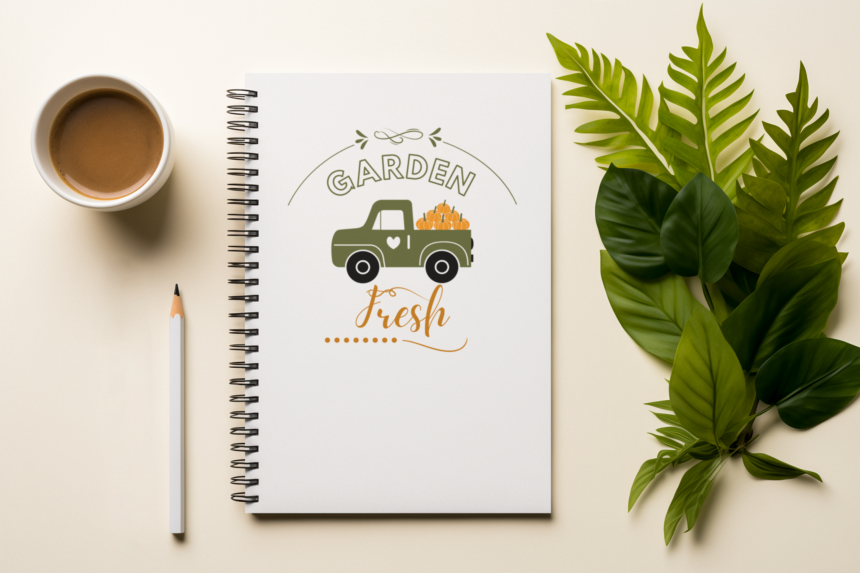 Notebook with 'Garden Fresh' design, cup of coffee, pencil, and leaves on a light surface