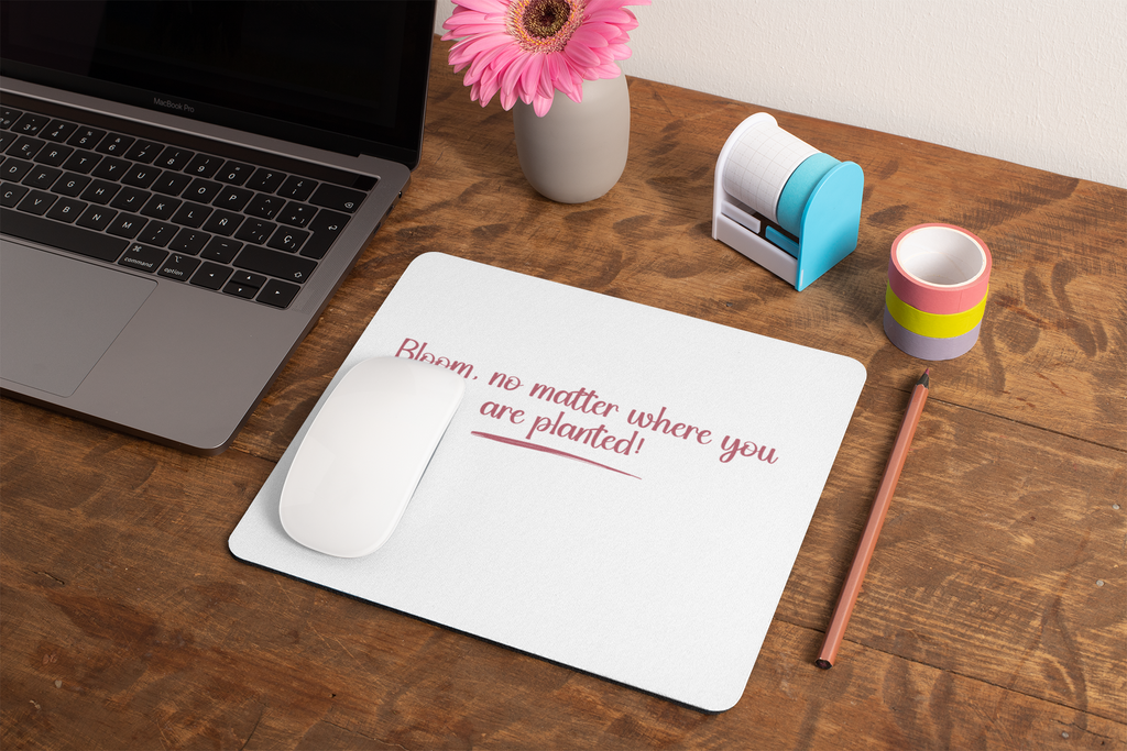 Laptop on a wooden desk with a mouse, mouse pad, and stationery items.
