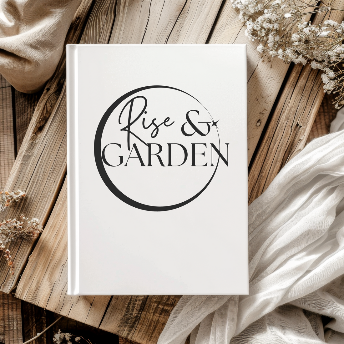 Notebook with 'Rise & Garden' on a wooden surface with dried flowers