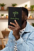 Person holding a black book titled 'Garden Strong' with a green tree logo.