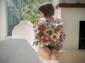 Person wearing a floral shirt sitting on a chair indoors
