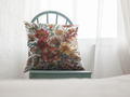 Floral-patterned pillow on a green chair against a white curtain background