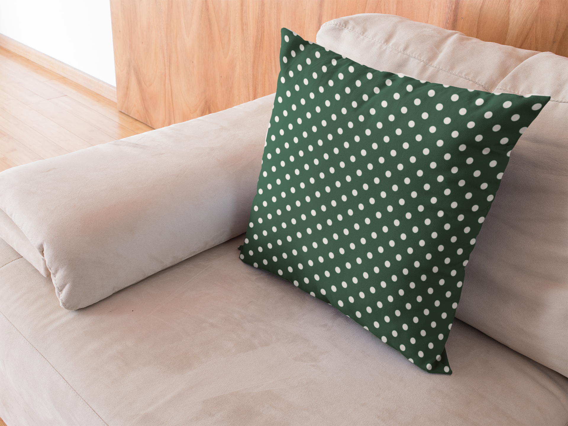 Green pillow with white polka dots on a beige couch