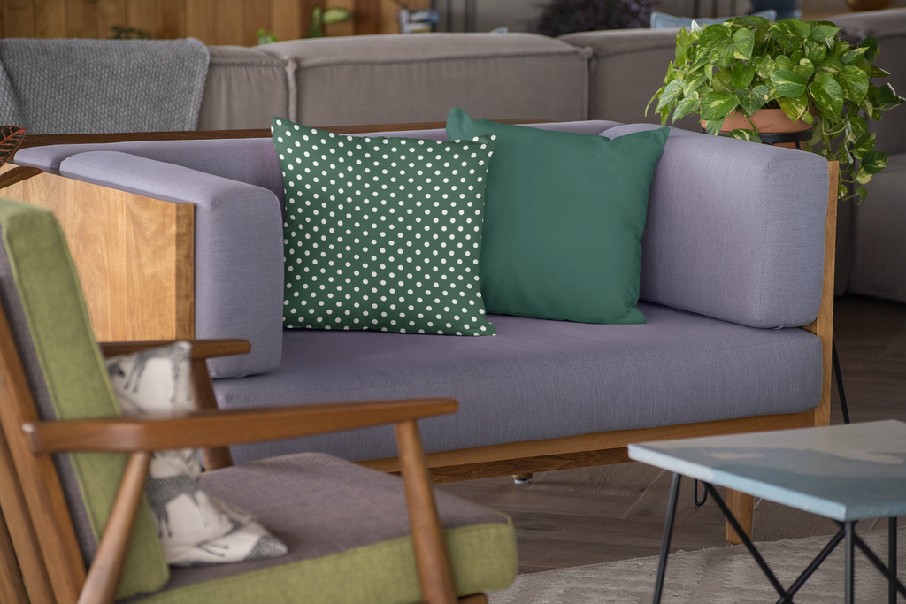 Gray sofa with green and white polka dot cushions, wooden armchair, and small table in a living room setting.