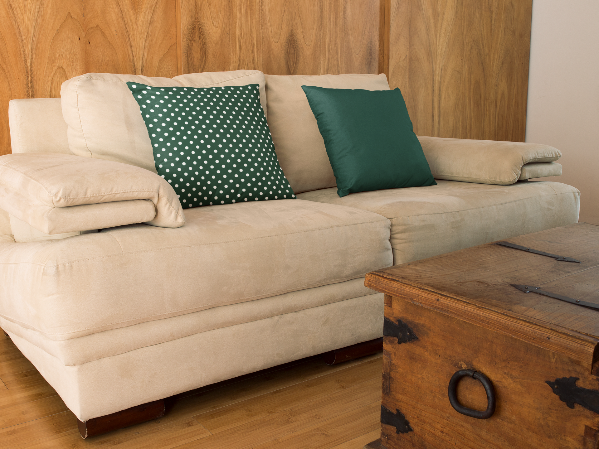 Beige sectional sofa with green pillows in a living room setting.