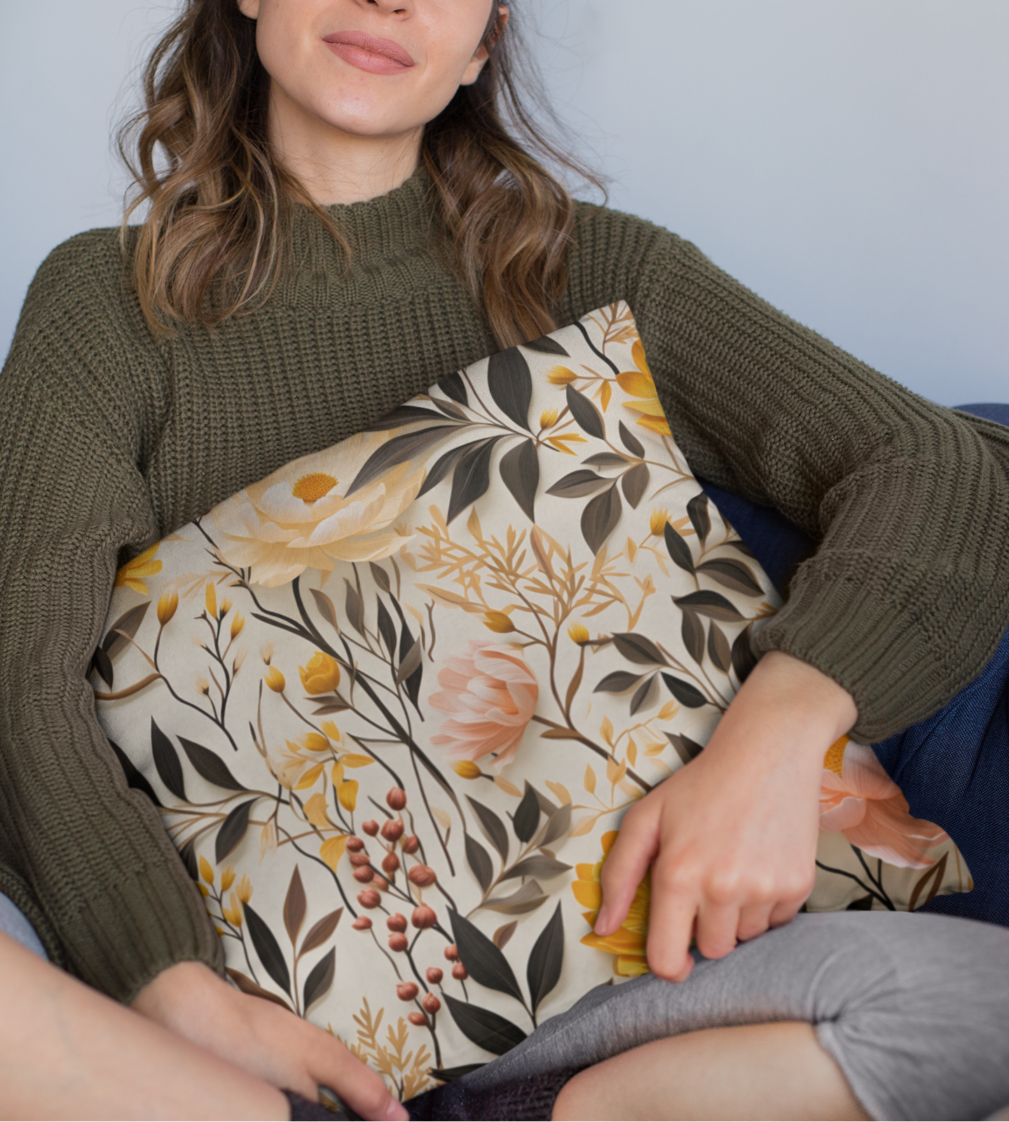 Woman holding a decorative pillow with floral and bird pattern against a plain background