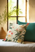 Floral-patterned pillow on a couch with a blurred plant and window in the background