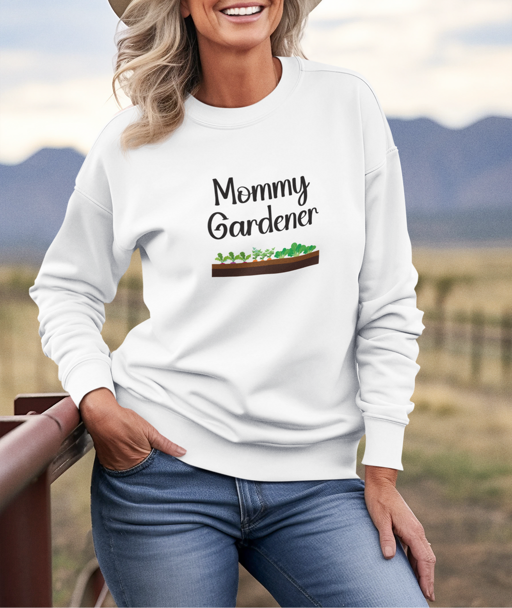 Woman wearing a white sweatshirt with 'Mommy Gardener' text and garden graphic, standing outdoors.
