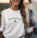 Woman wearing a 'Merry Christmas' sweater standing next to a horse with a sunset background
