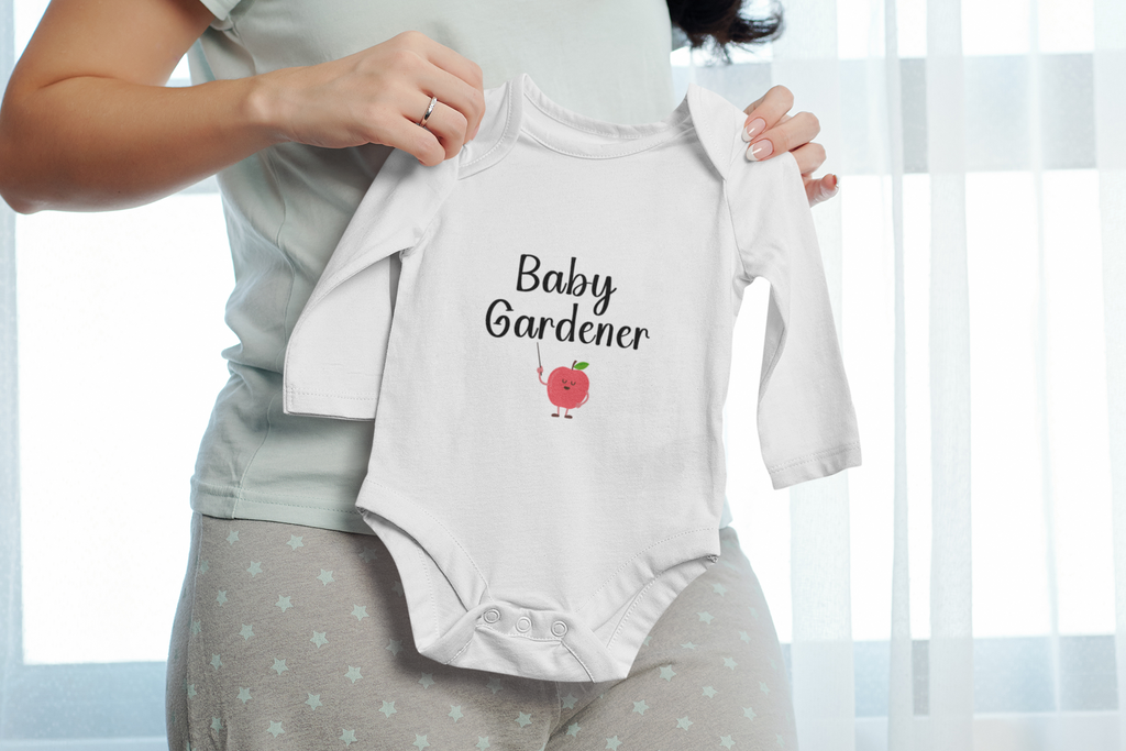 Person holding a baby onesie with 'Baby Gardener' text and apple graphic.