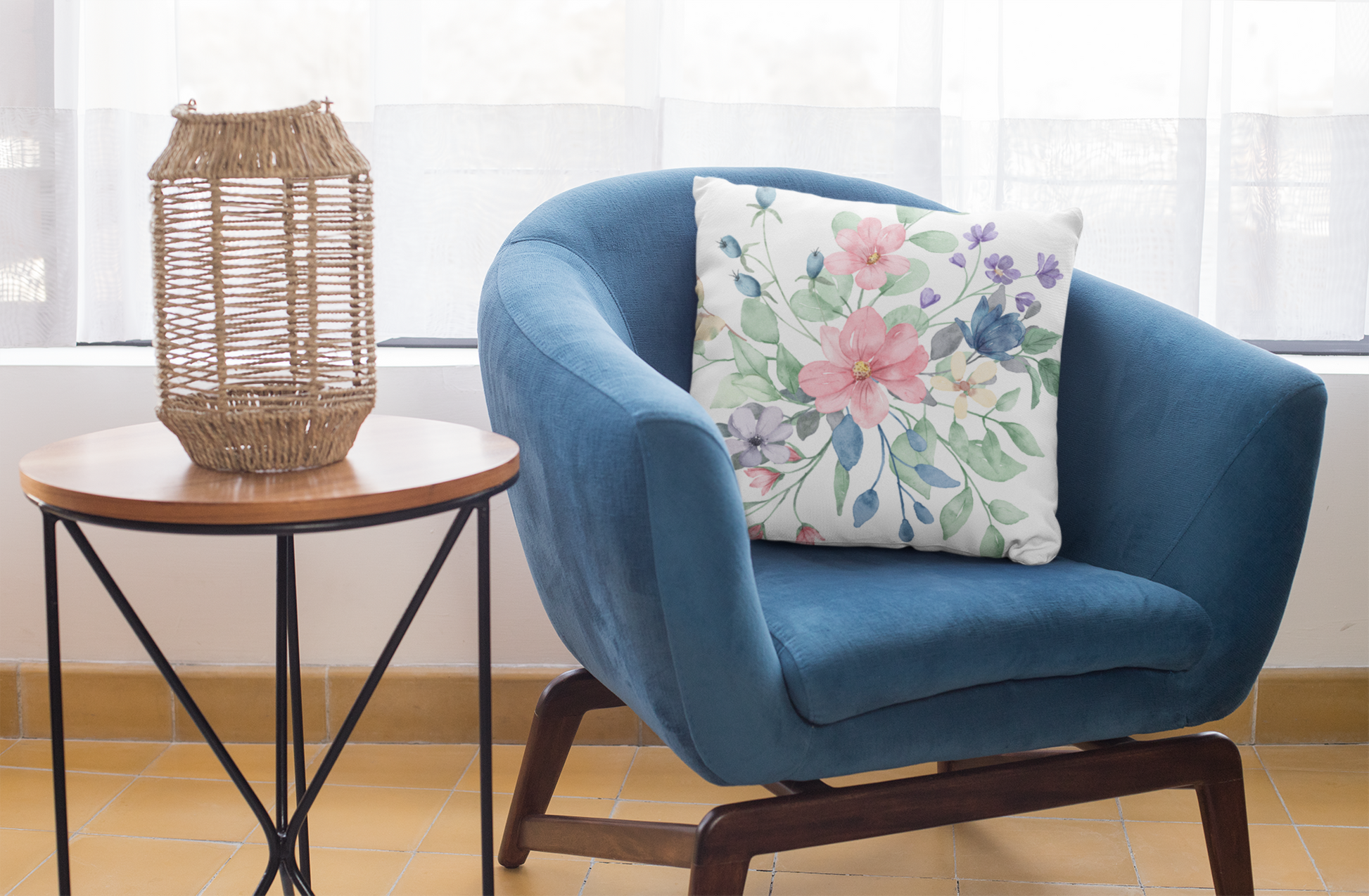 Blue armchair with a floral pillow next to a side table with a woven lantern, in a bright room.