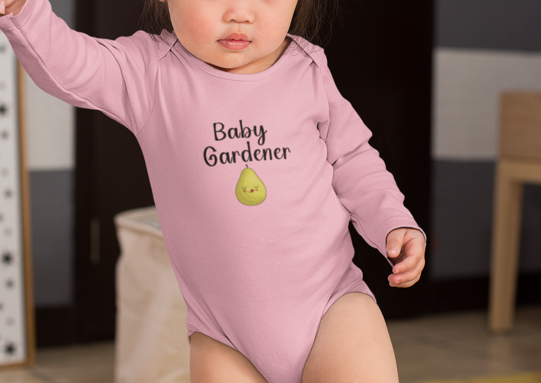 Child wearing a green 'Baby Gardener' onesie in a cozy room with pillows and a couch.