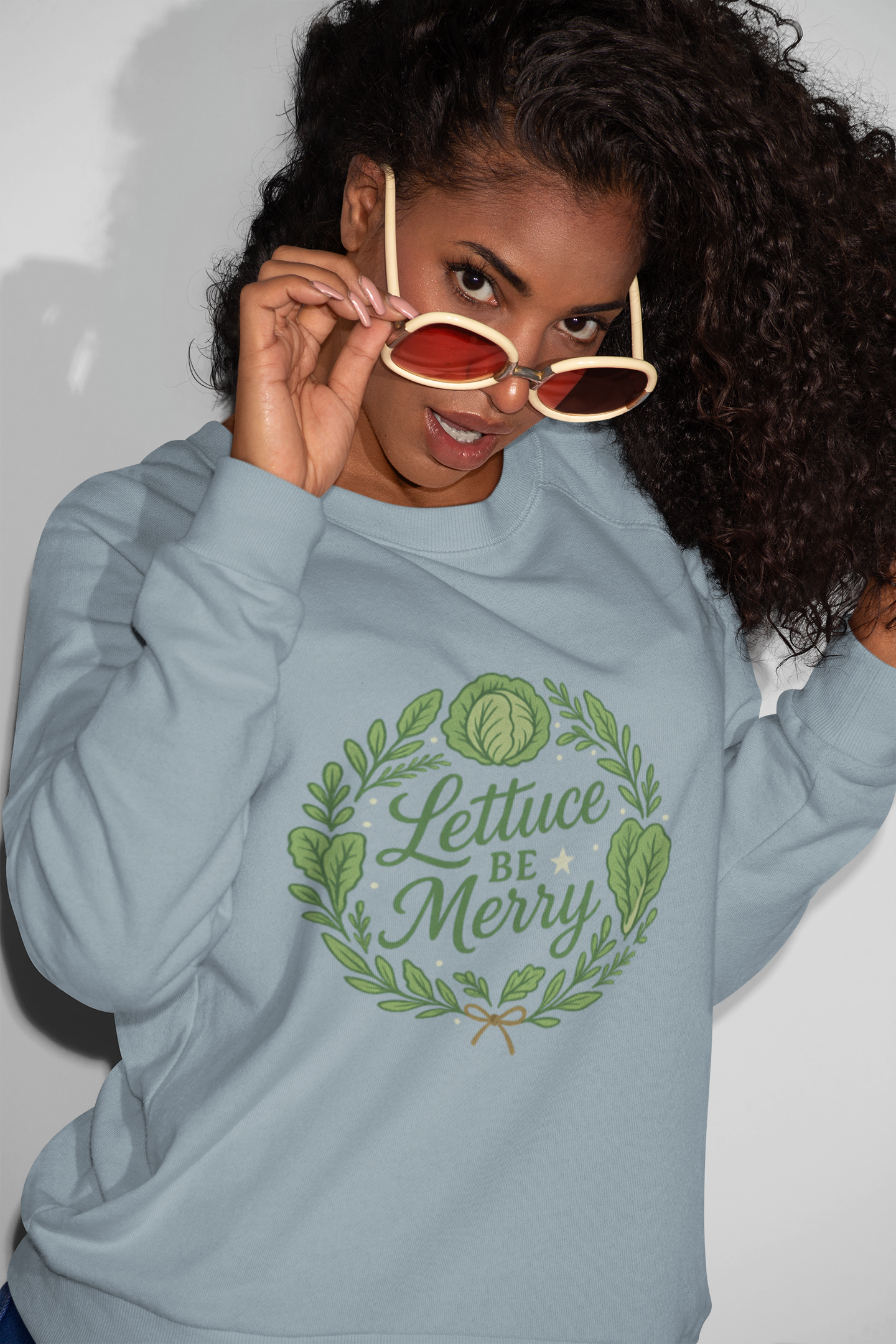 Person wearing a light blue hoodie with 'Lettuce Be Merry' text and leaf design.
