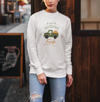 Woman wearing a white sweatshirt with a graphic design standing in front of a wooden door.
