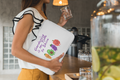 Person holding a white bag with colorful designs in a cafe setting