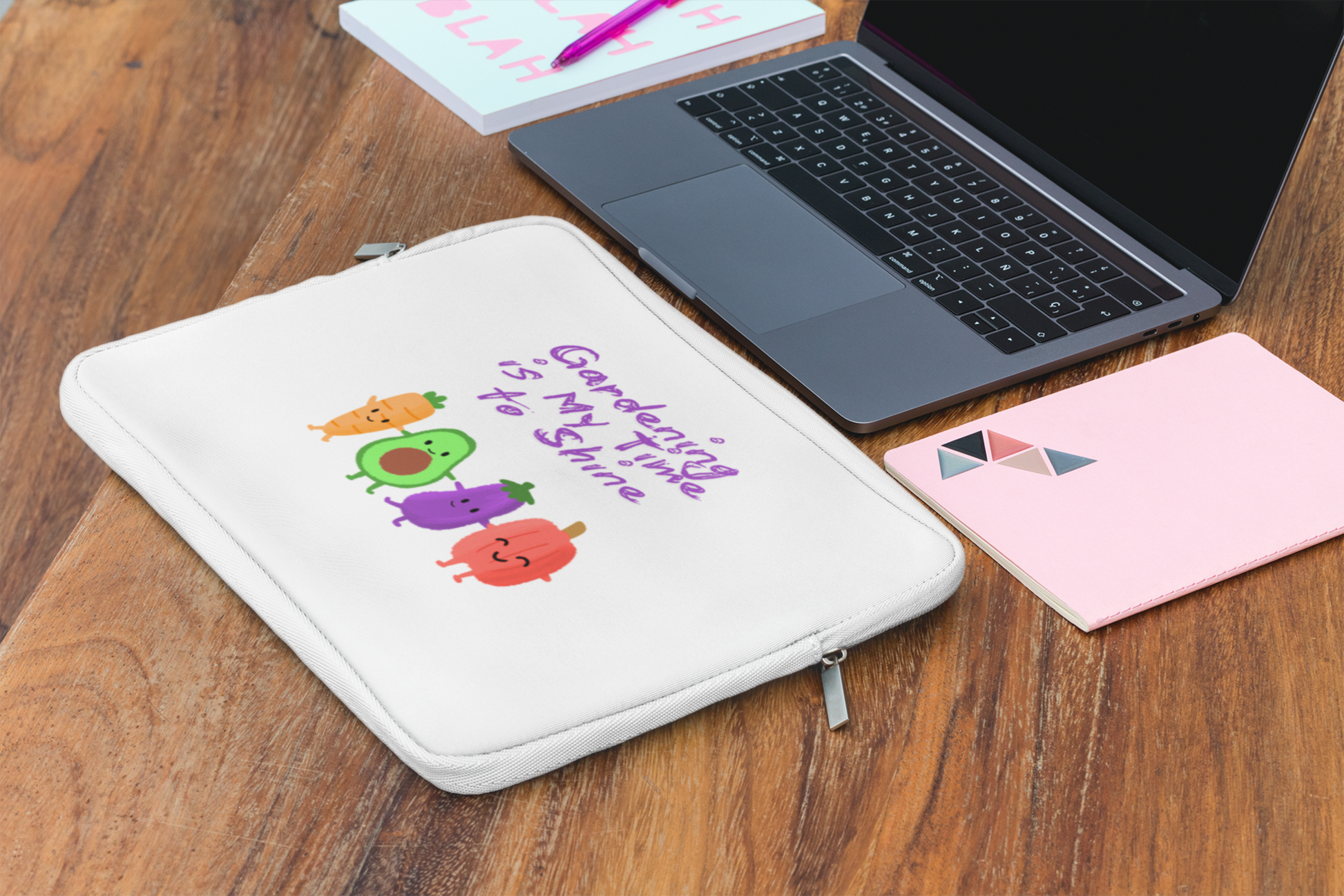 White pouch with colorful designs and text on a wooden surface with a laptop and notebook.