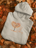 Light gray hoodie with autumn-themed design on a bed of leaves