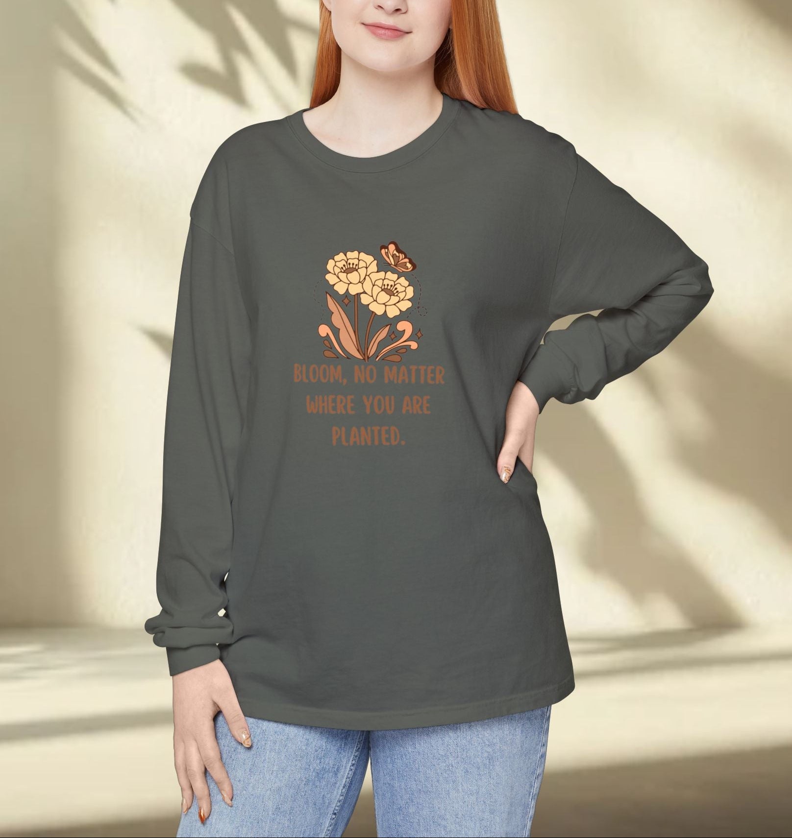 Woman wearing a dark gray long-sleeve shirt with a floral design and text, standing against a neutral background.