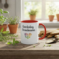 White mug with red interior and handle on a wooden table with gardening tools and plants.