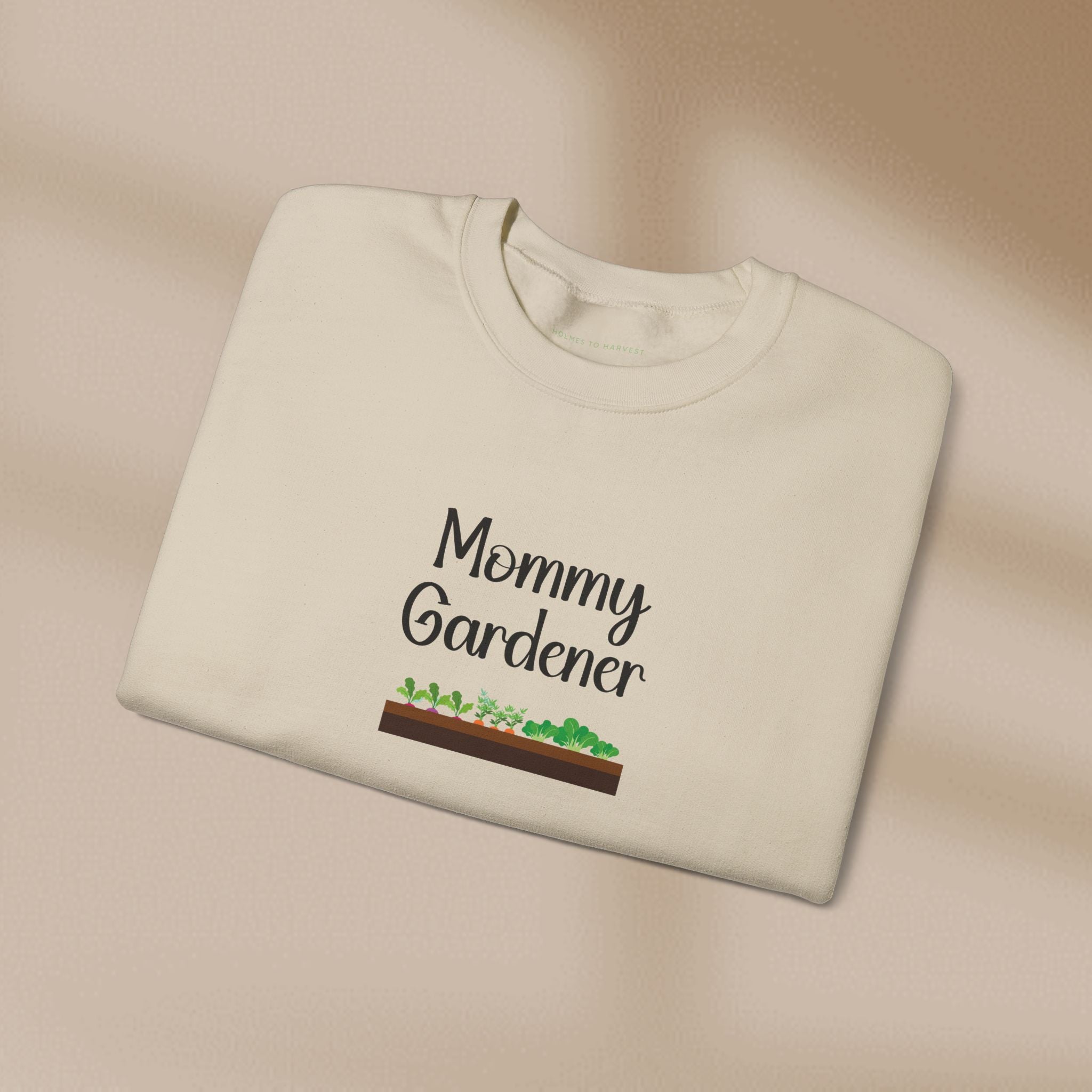 Folded beige sweatshirt with 'Mommy Gardener' text and garden graphic on a beige background