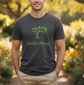 Man wearing a 'Garden Strong' t-shirt with a tree design in a garden setting