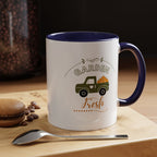 White mug with blue interior and handle, featuring a truck and 'Garden Fresh' text, on a wooden surface with coffee beans and a spoon.