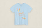 Light blue t-shirt with 'Spring Into Gardening' text and floral designs on a white background