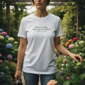 Person wearing a white t-shirt with text in a garden