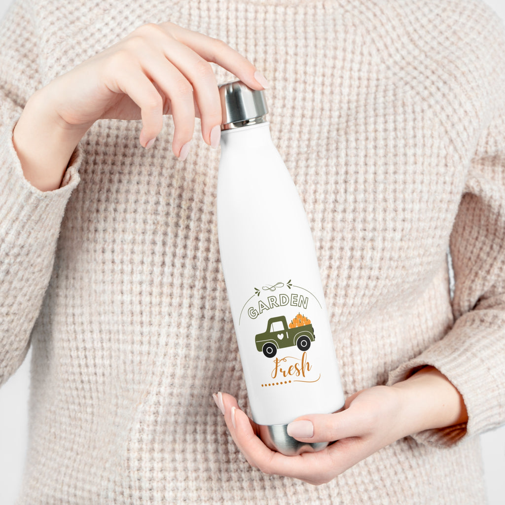 Person holding a white water bottle with a 'Garden Fresh' design on a beige background